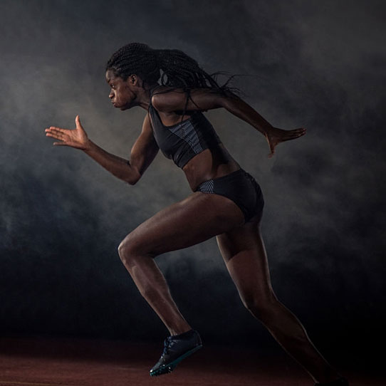 Female athlete sprinting on a track against a dark background