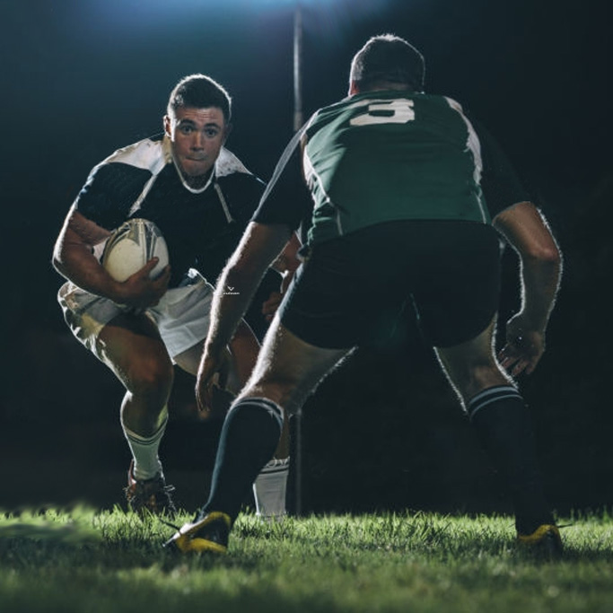 Rugby player carrying the ball towards two defending players