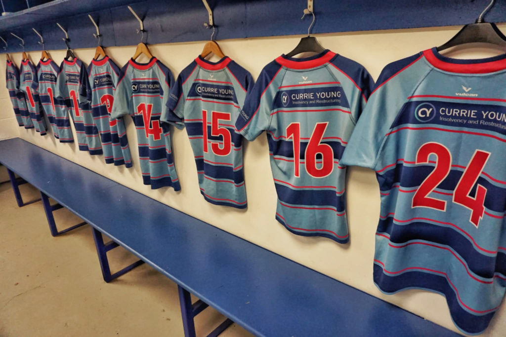 Custom rugby shirts hanging in changing room before match