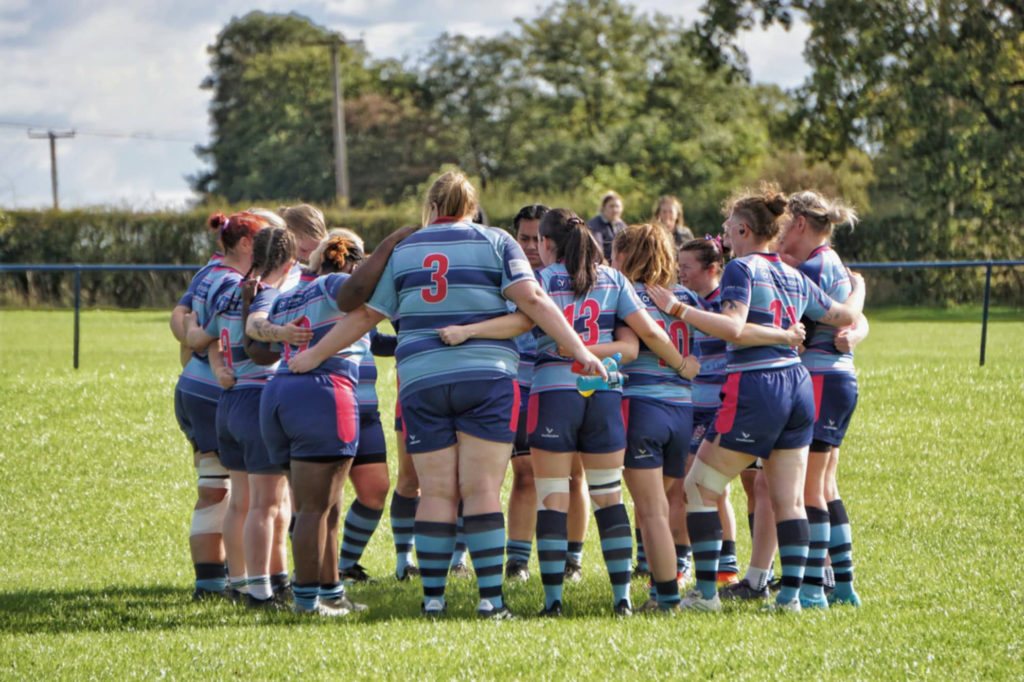 Women’s rugby players wearing custom blue and maroon rugby kit during a match