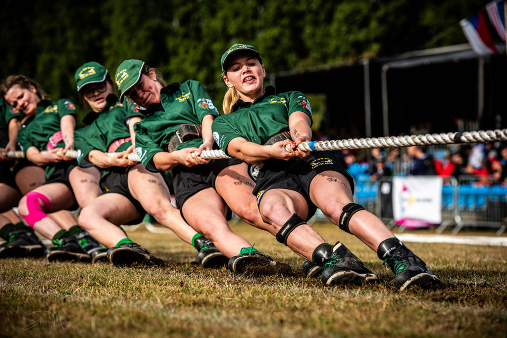 Tug of war team in green custom sports kit competing outdoors