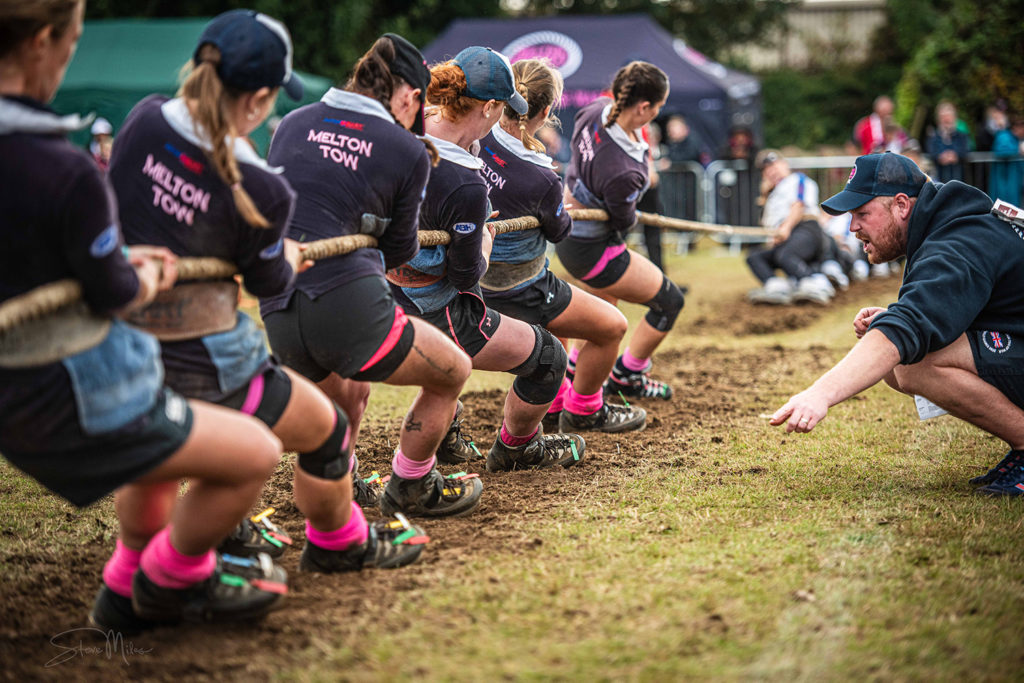 Tug of war team wearing custom navy and pink kit during competition