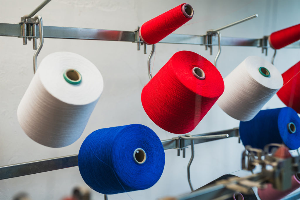Red, white and blue yarn cones used for circular knitting machine fabric production.