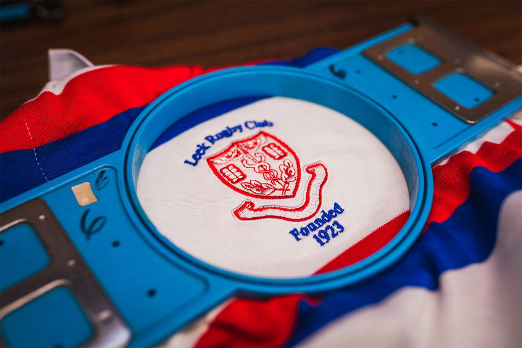Embroidery frame positioned around a Leek Rugby club badge on a traditional rugby shirt.