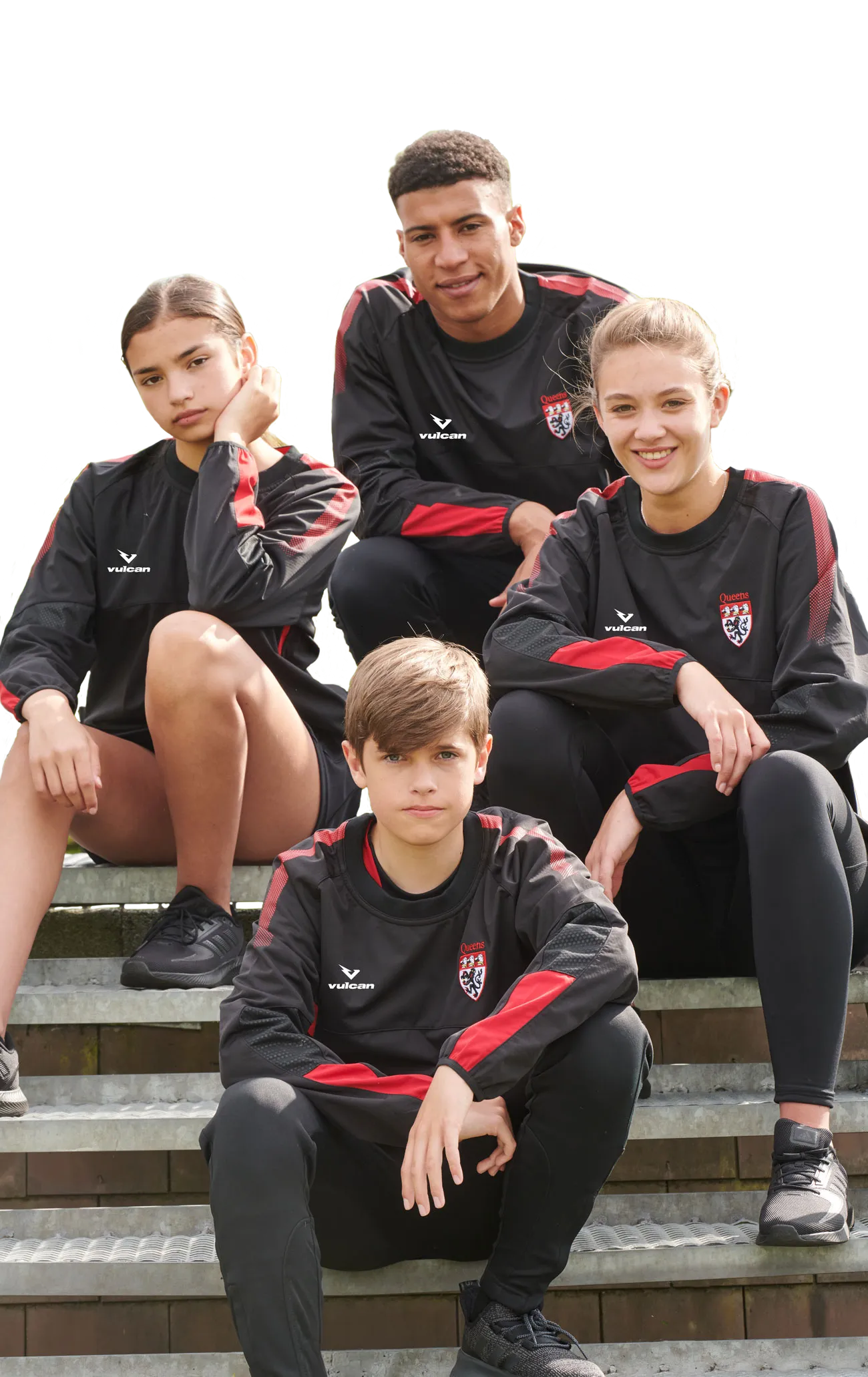 Four young athletes wearing black and red Vulcan Sports training wear