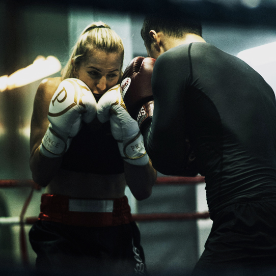 Female boxer training with a coach inside a boxing ring
