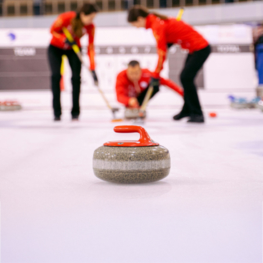 Curling stone on the ice with players in the background